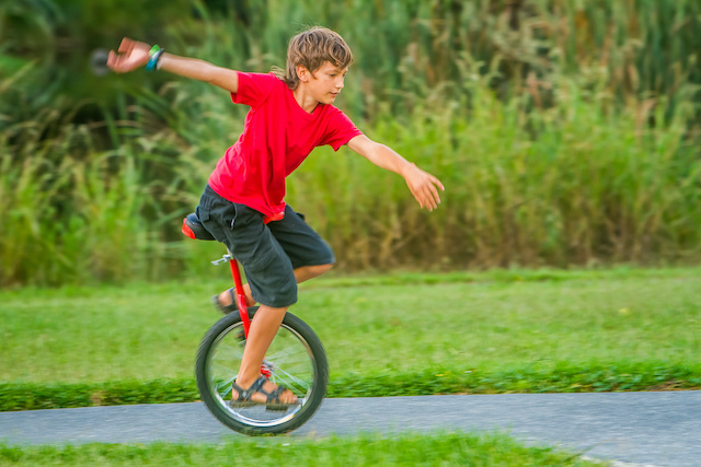 ジャパンボックス | A boy riding a unicycle in the greenery. 
